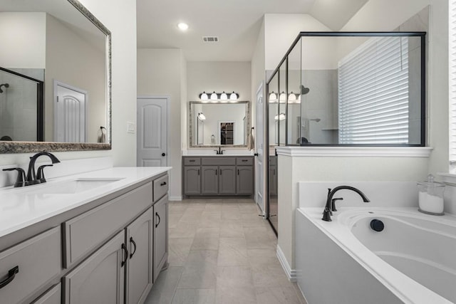 full bathroom featuring two vanities, visible vents, a stall shower, a sink, and a bath