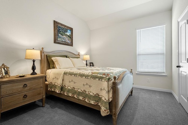 bedroom with dark colored carpet, vaulted ceiling, and baseboards