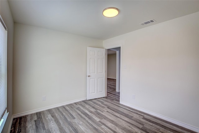spare room with visible vents, baseboards, and wood finished floors