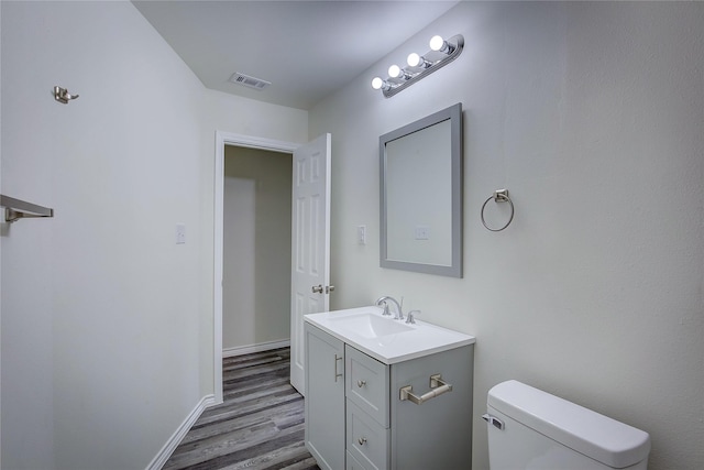 bathroom with visible vents, baseboards, toilet, wood finished floors, and vanity