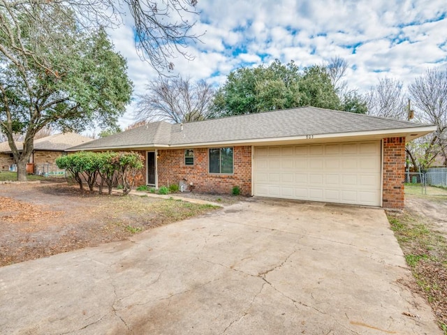 ranch-style house featuring an attached garage, fence, concrete driveway, and brick siding