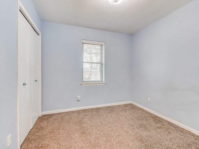 unfurnished bedroom featuring a closet, baseboards, and carpet flooring