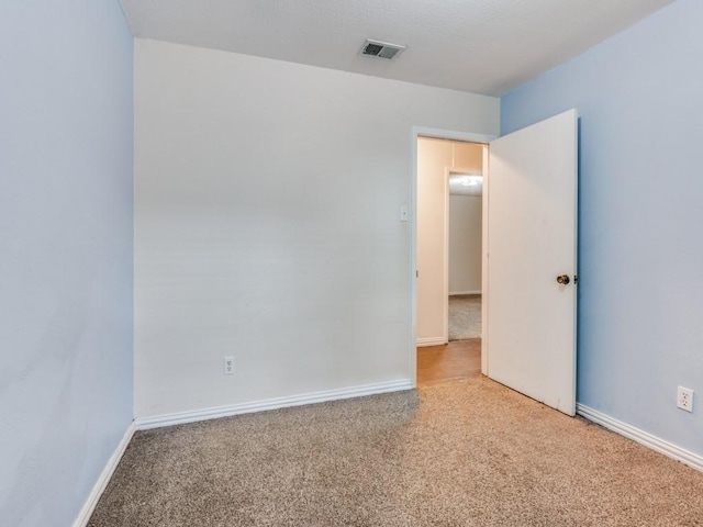 empty room featuring carpet flooring, visible vents, and baseboards