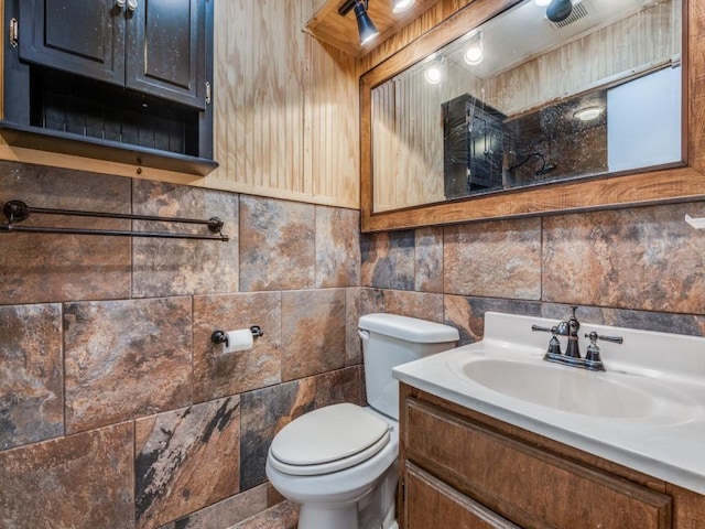 bathroom featuring toilet, visible vents, tile walls, and vanity