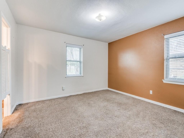 carpeted empty room featuring baseboards