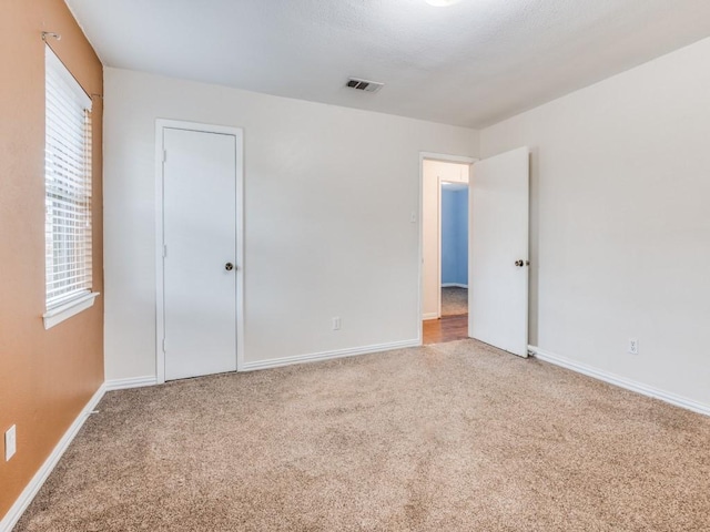 unfurnished bedroom featuring carpet flooring, visible vents, and baseboards