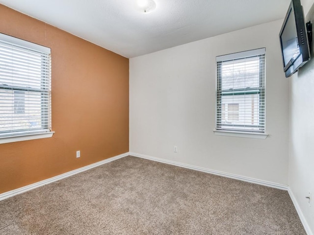 spare room featuring carpet and baseboards