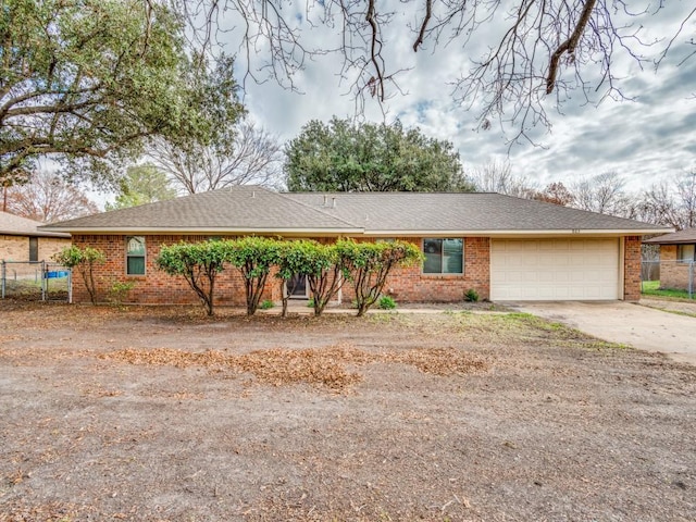 ranch-style house featuring a garage, driveway, brick siding, and fence