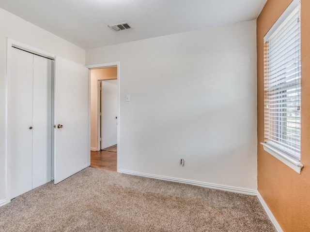 unfurnished bedroom with carpet floors, baseboards, visible vents, and a closet