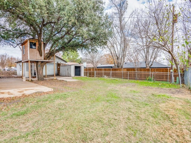 view of yard with a garage, fence, and an outdoor structure