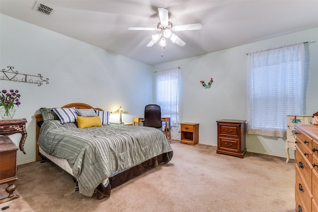 bedroom with light carpet, ceiling fan, visible vents, and baseboards