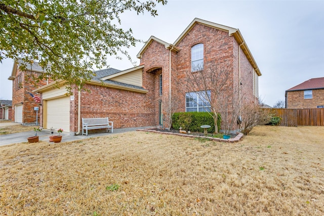 traditional-style house with a front yard, brick siding, fence, and an attached garage