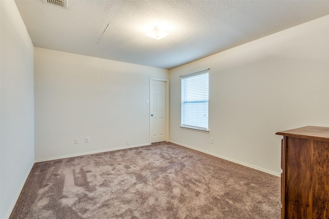 carpeted empty room with a textured ceiling, visible vents, and baseboards