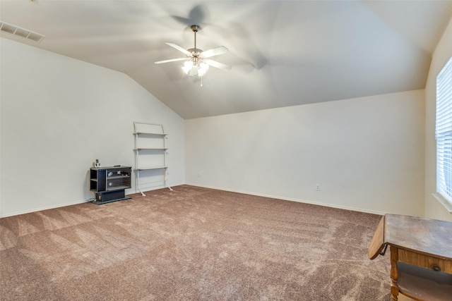 empty room featuring lofted ceiling, visible vents, a ceiling fan, and carpet flooring