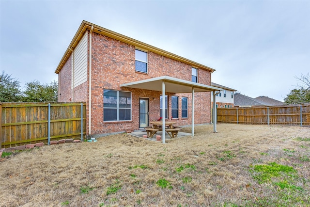 rear view of house with brick siding, a patio, and a fenced backyard