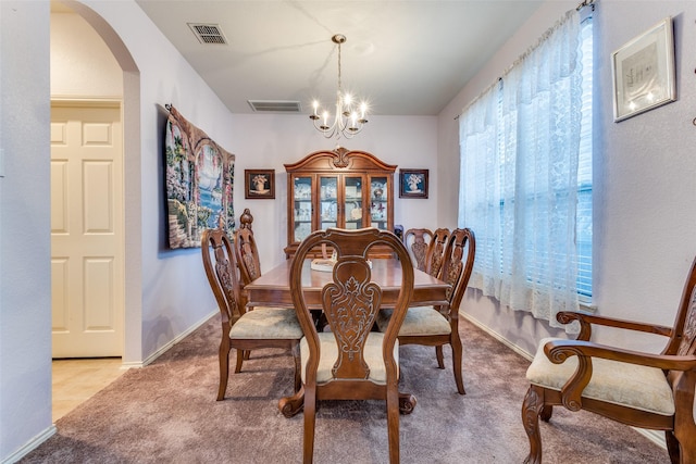 carpeted dining space with a chandelier, arched walkways, visible vents, and baseboards