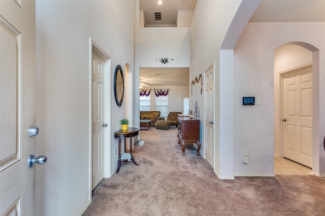 hallway featuring arched walkways, carpet, visible vents, and baseboards