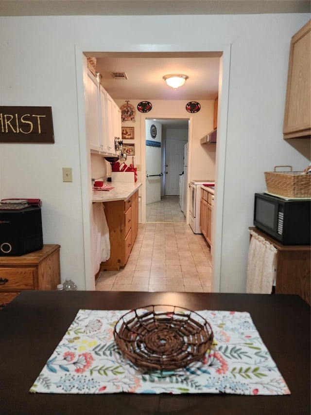 kitchen featuring white electric stove, visible vents, light countertops, black microwave, and light tile patterned flooring