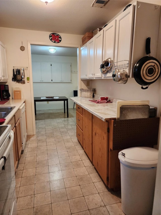 kitchen with range with electric stovetop, a sink, white cabinetry, light countertops, and dishwasher