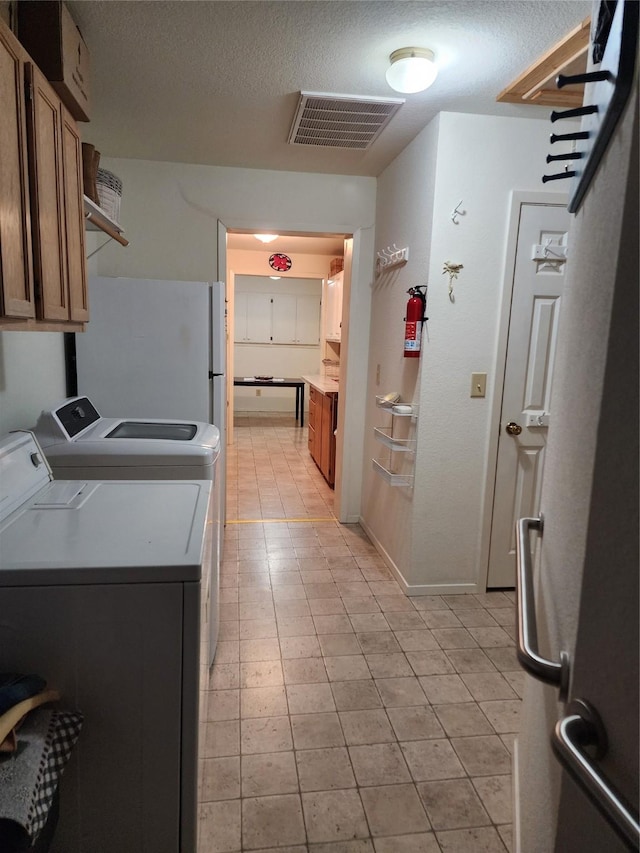 laundry room with cabinet space, visible vents, separate washer and dryer, and a textured ceiling