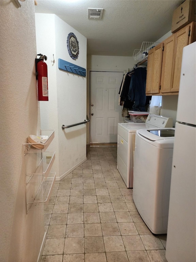 washroom with cabinet space, visible vents, washing machine and clothes dryer, a textured ceiling, and light tile patterned flooring