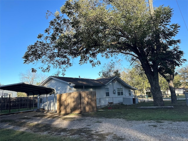 view of property exterior featuring driveway, fence, and a detached carport