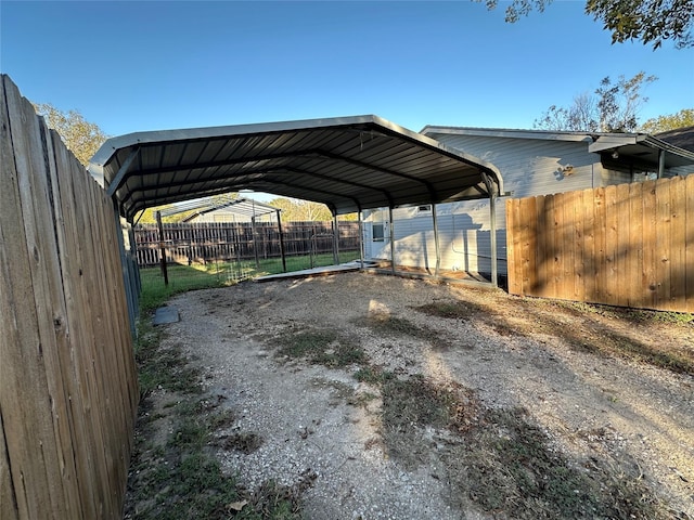 view of car parking with driveway, fence, and a detached carport