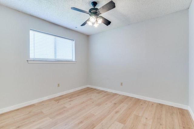 spare room featuring a textured ceiling, ceiling fan, light wood-style flooring, and baseboards