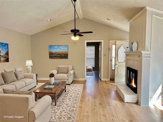 living area with light wood-style floors, a brick fireplace, vaulted ceiling with beams, and baseboards