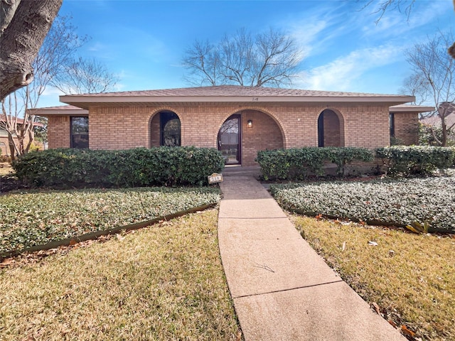 view of front of property featuring brick siding and a front lawn