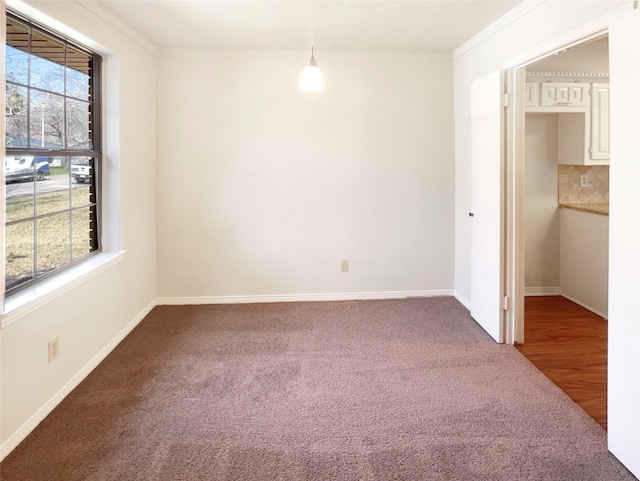 unfurnished room with baseboards, carpet flooring, a wealth of natural light, and crown molding