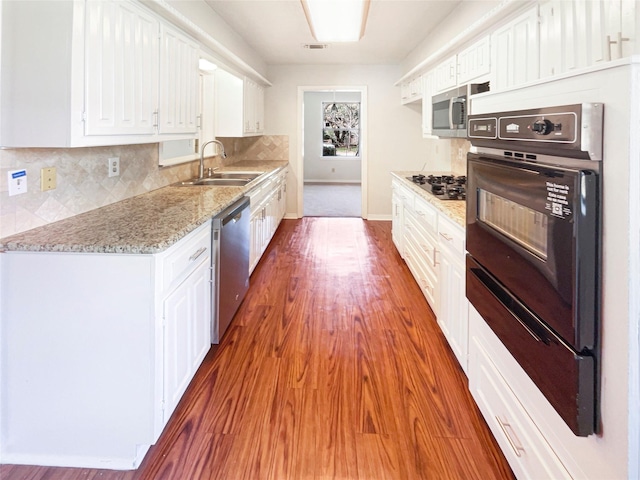 kitchen with wood finished floors, a sink, visible vents, white cabinets, and black appliances