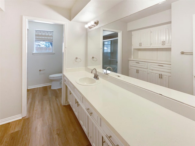 bathroom featuring vanity, wood finished floors, toilet, and baseboards