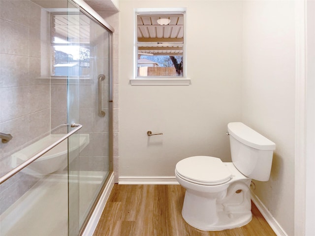 bathroom featuring baseboards, a shower stall, toilet, and wood finished floors