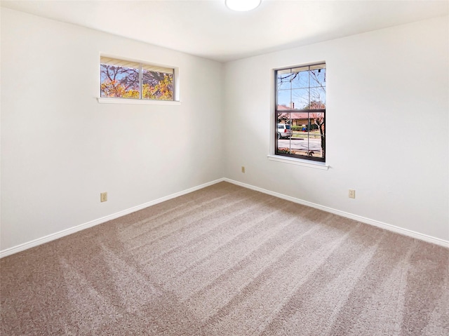 carpeted empty room featuring baseboards