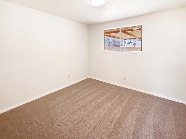 carpeted empty room featuring baseboards