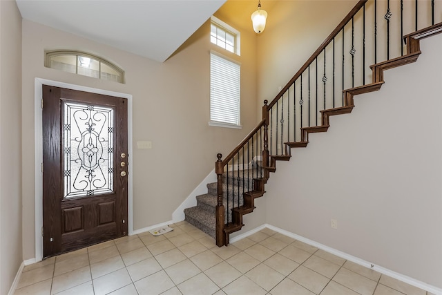 entrance foyer with stairs, light tile patterned flooring, and baseboards