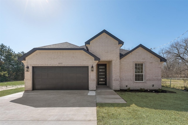 view of front of house featuring a front yard, concrete driveway, brick siding, and an attached garage