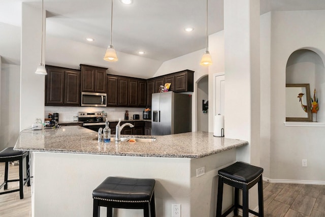 kitchen featuring appliances with stainless steel finishes, a breakfast bar area, a sink, and light stone countertops