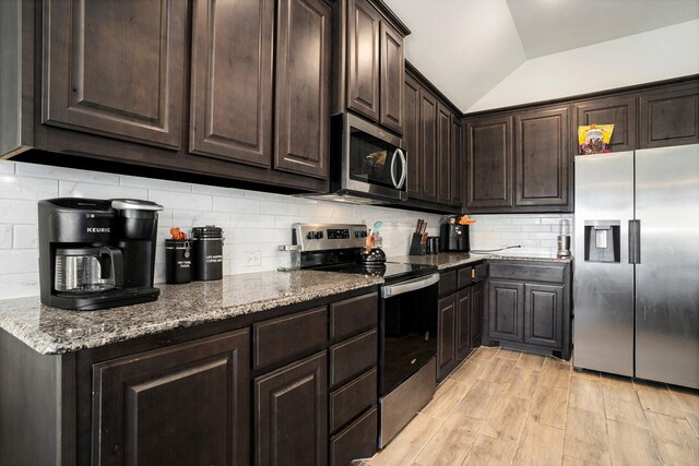 kitchen with stone countertops, decorative backsplash, lofted ceiling, stainless steel appliances, and dark brown cabinets