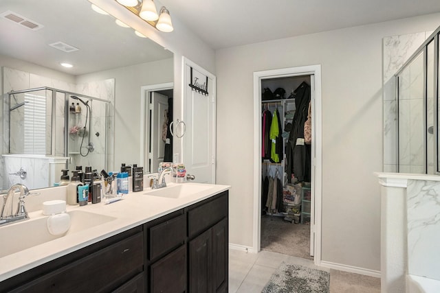 bathroom featuring a spacious closet, a sink, visible vents, and a shower stall