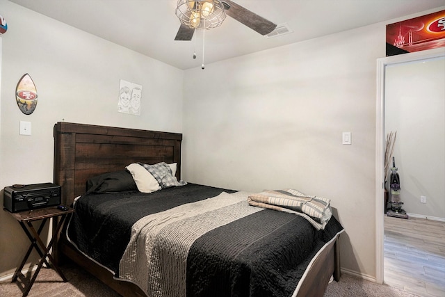 bedroom with baseboards, visible vents, a ceiling fan, and wood finished floors