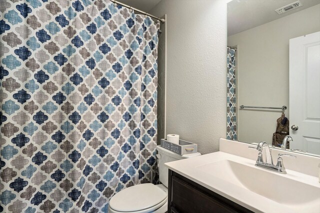 full bathroom with curtained shower, visible vents, a textured wall, toilet, and vanity