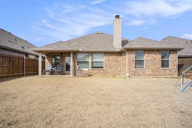 back of property with a chimney, a patio area, brick siding, and a fenced backyard