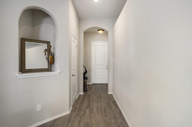 hallway with dark wood finished floors and baseboards