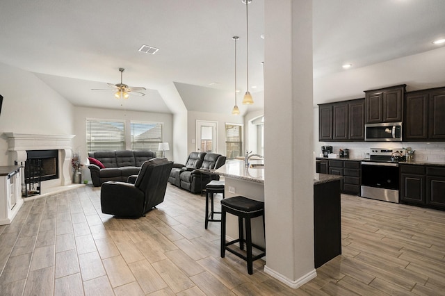 kitchen featuring a breakfast bar area, visible vents, light wood-style floors, open floor plan, and appliances with stainless steel finishes