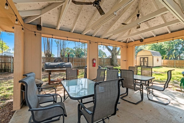 view of patio / terrace featuring a fenced backyard, an outbuilding, outdoor dining area, and a shed