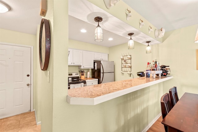 kitchen featuring white cabinets, a peninsula, stainless steel appliances, light countertops, and a kitchen bar