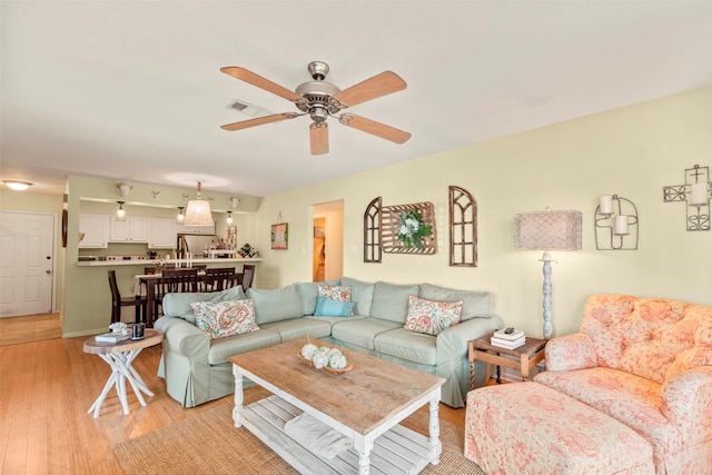 living room with a ceiling fan, light wood finished floors, and visible vents