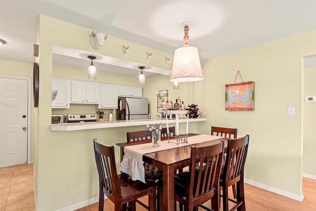 dining area featuring baseboards and light wood-type flooring